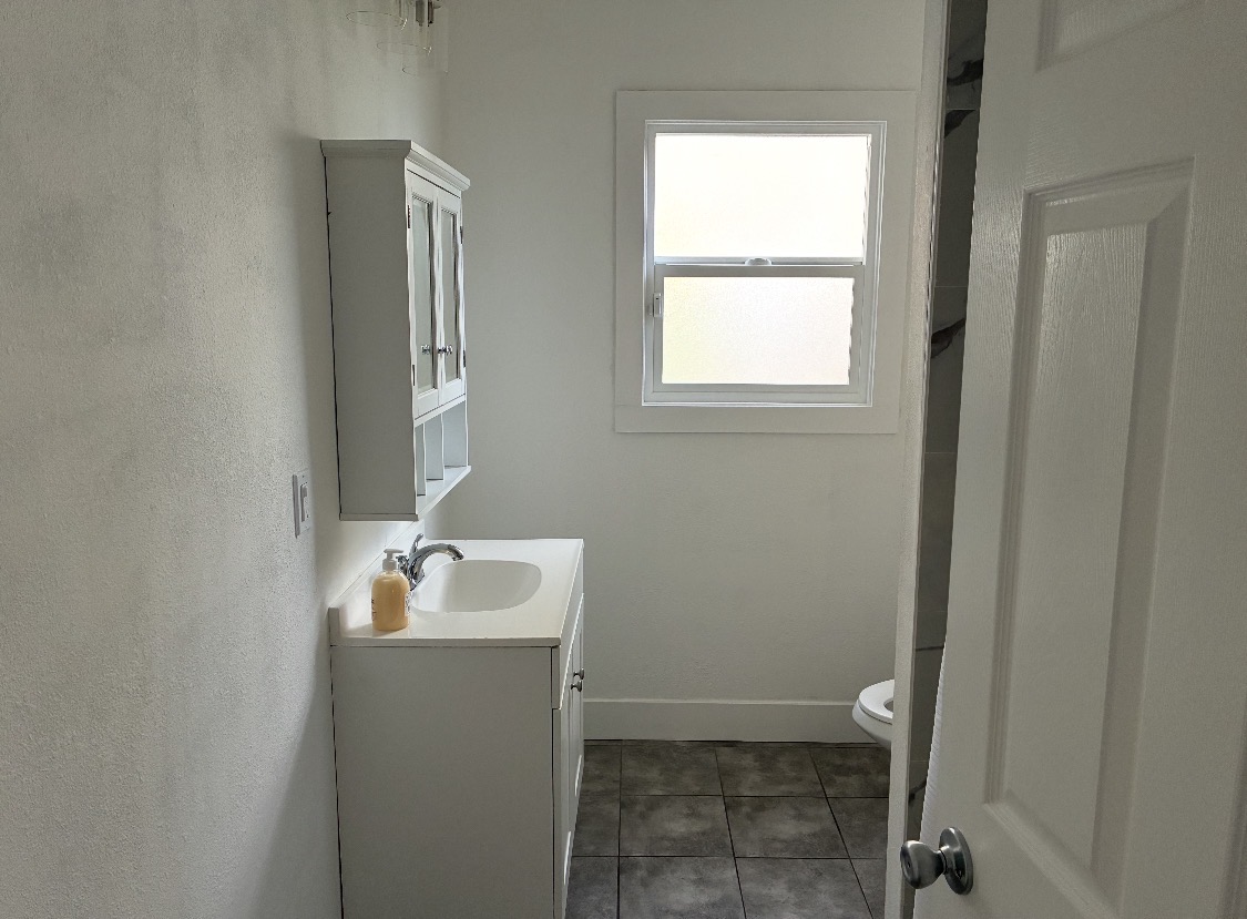 Clean, bright bathroom with vanity, mirrored cabinet, and window
