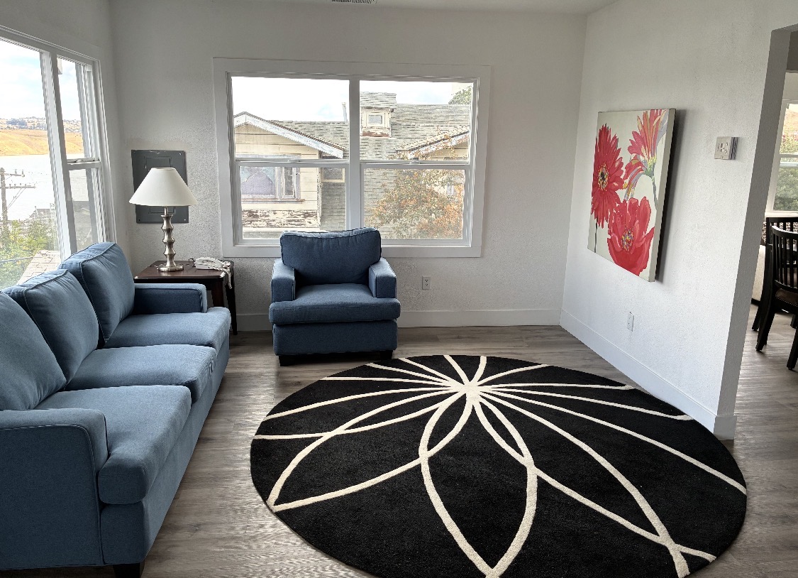 Bright living room with blue sofa, armchair, and large windows